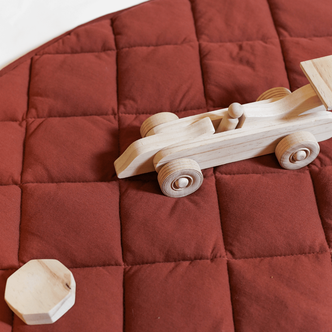 Rust color jersey quilted play mat with waterproof backing and wooden toy car on top