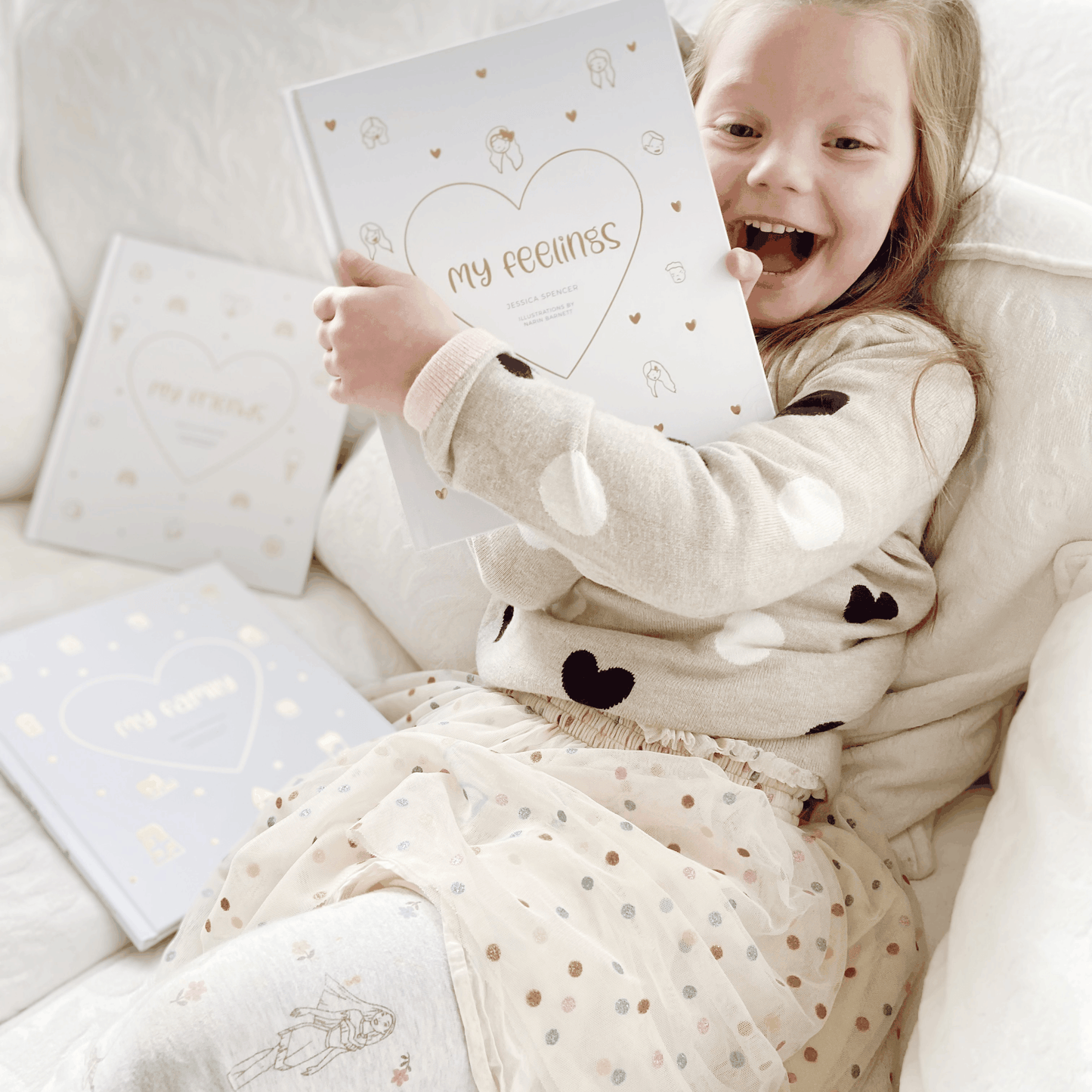 Child holding My Feelings - Illustrated Children's Book with gold foil heart design on white cover