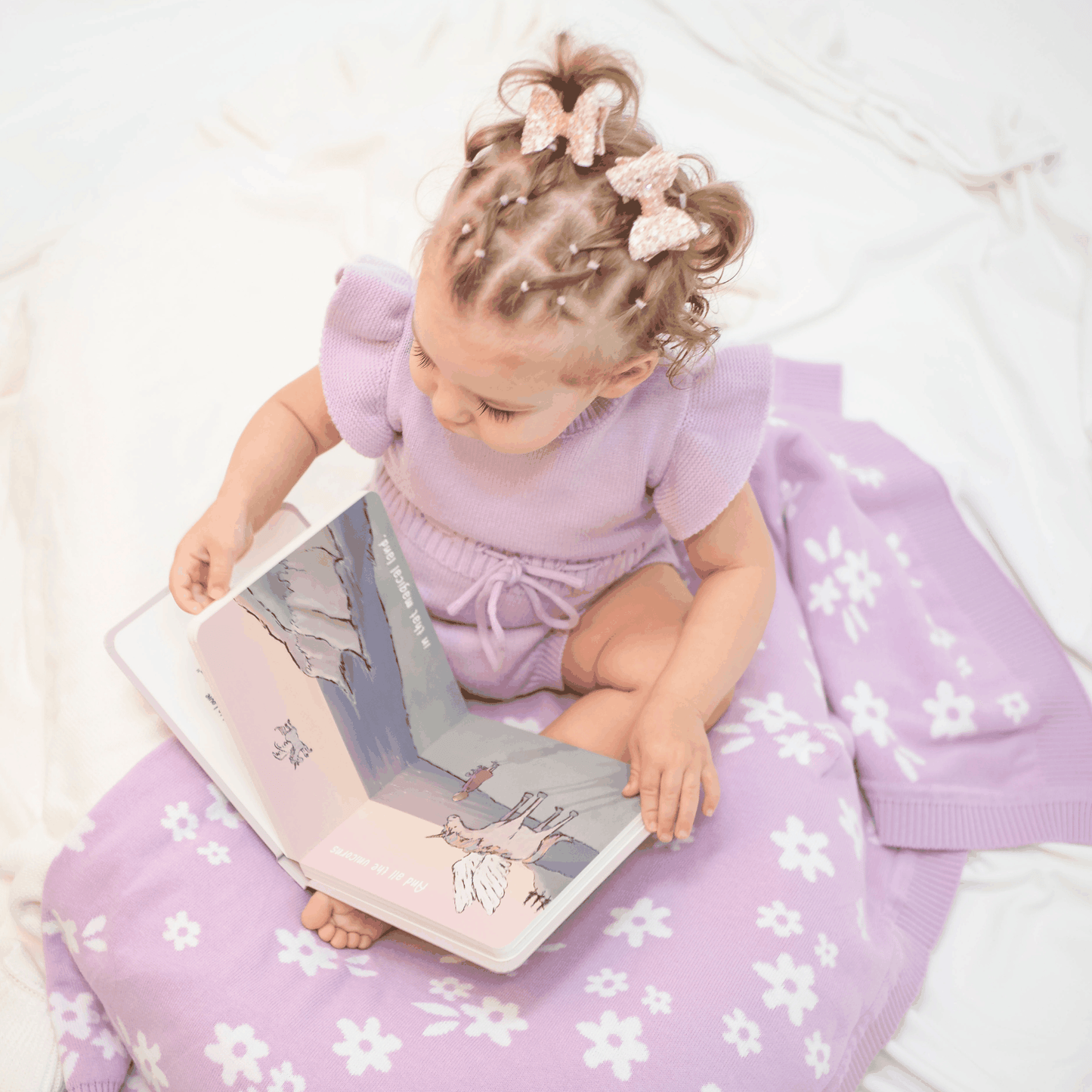 Baby reading Love you all the Roars board book with purple floral blanket