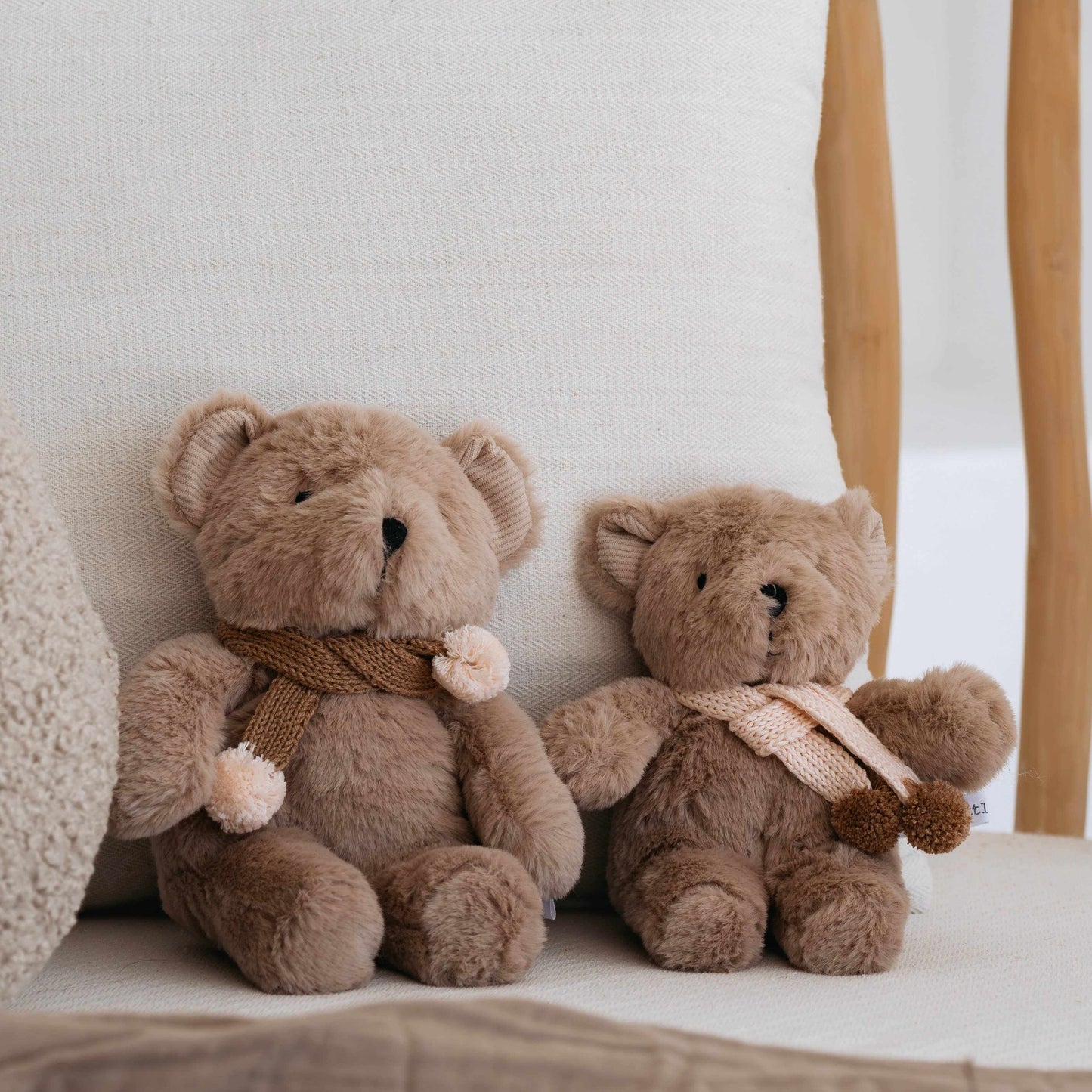 Prudence the Bear caramel plush with knitted merino wool scarf and pink pom poms sitting on a chair