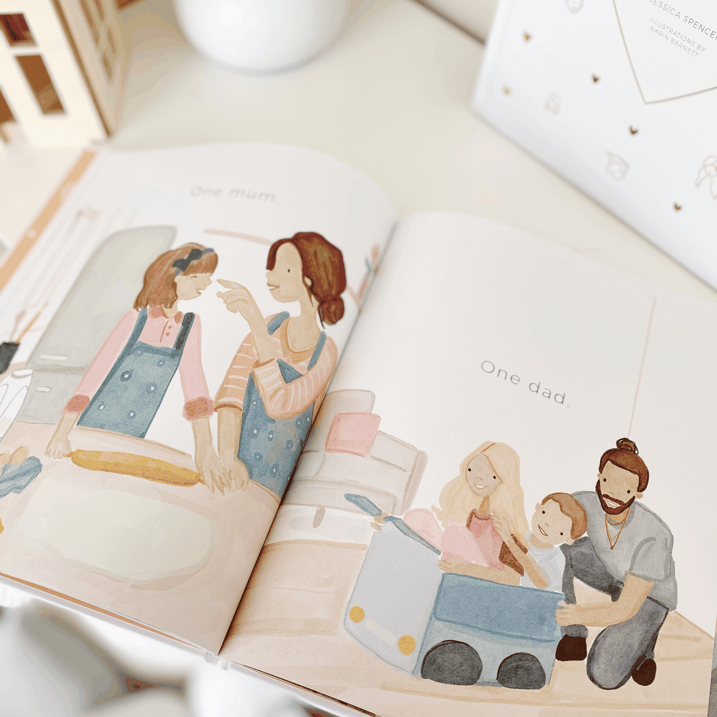 The My Series children's book open to illustrated family scenes with gold foil and white cover design
