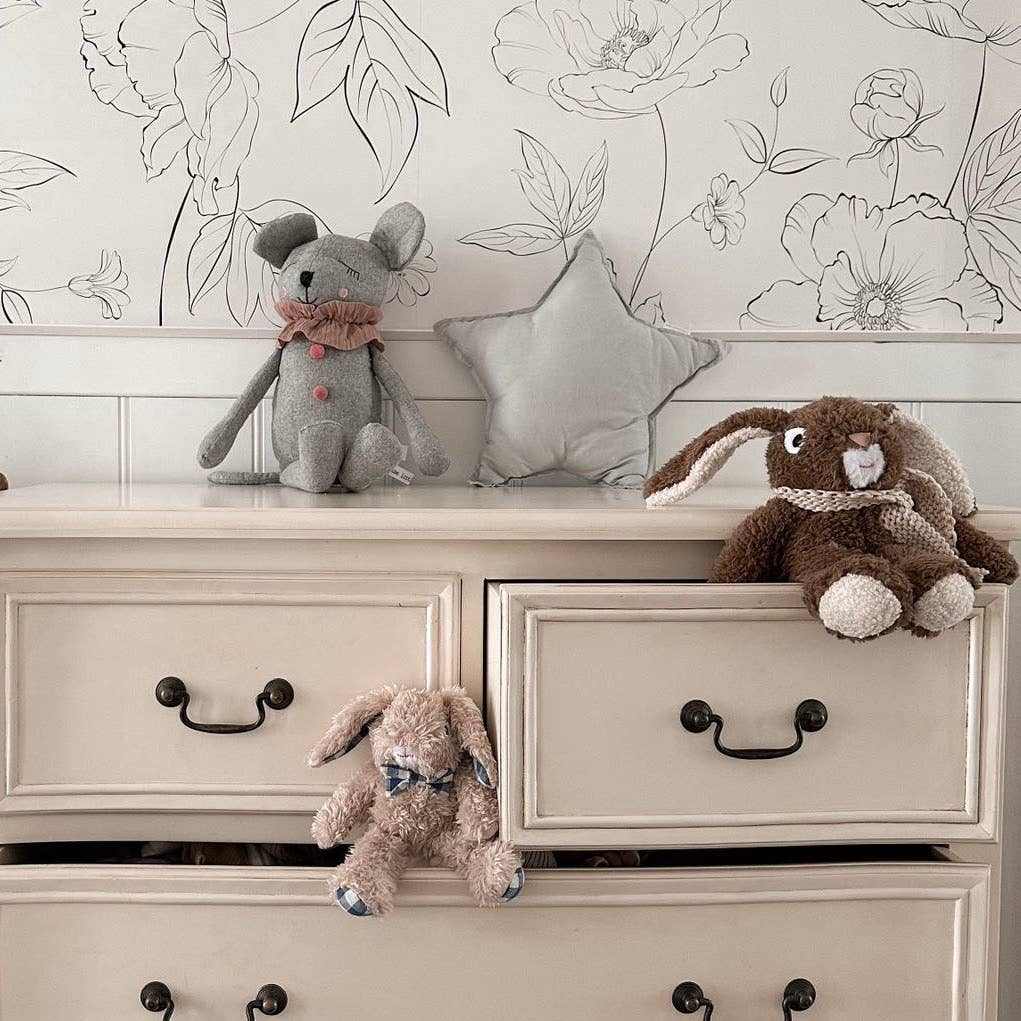 Louis Jr. the Bunny plush stuffed animal with floppy ears sitting on a beige dresser drawer