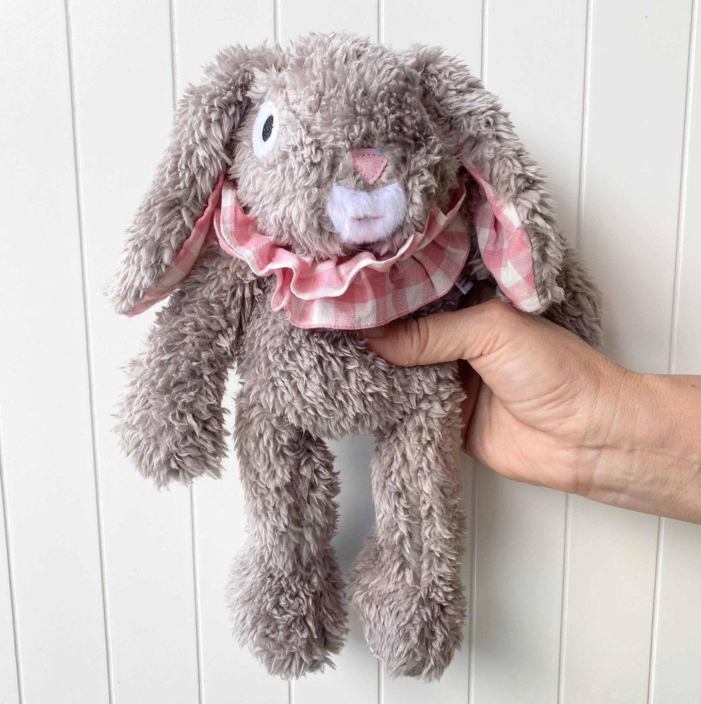 Eloise the Bunny soft plush toy with floppy ears and pink checkered ruffle collar held by hand