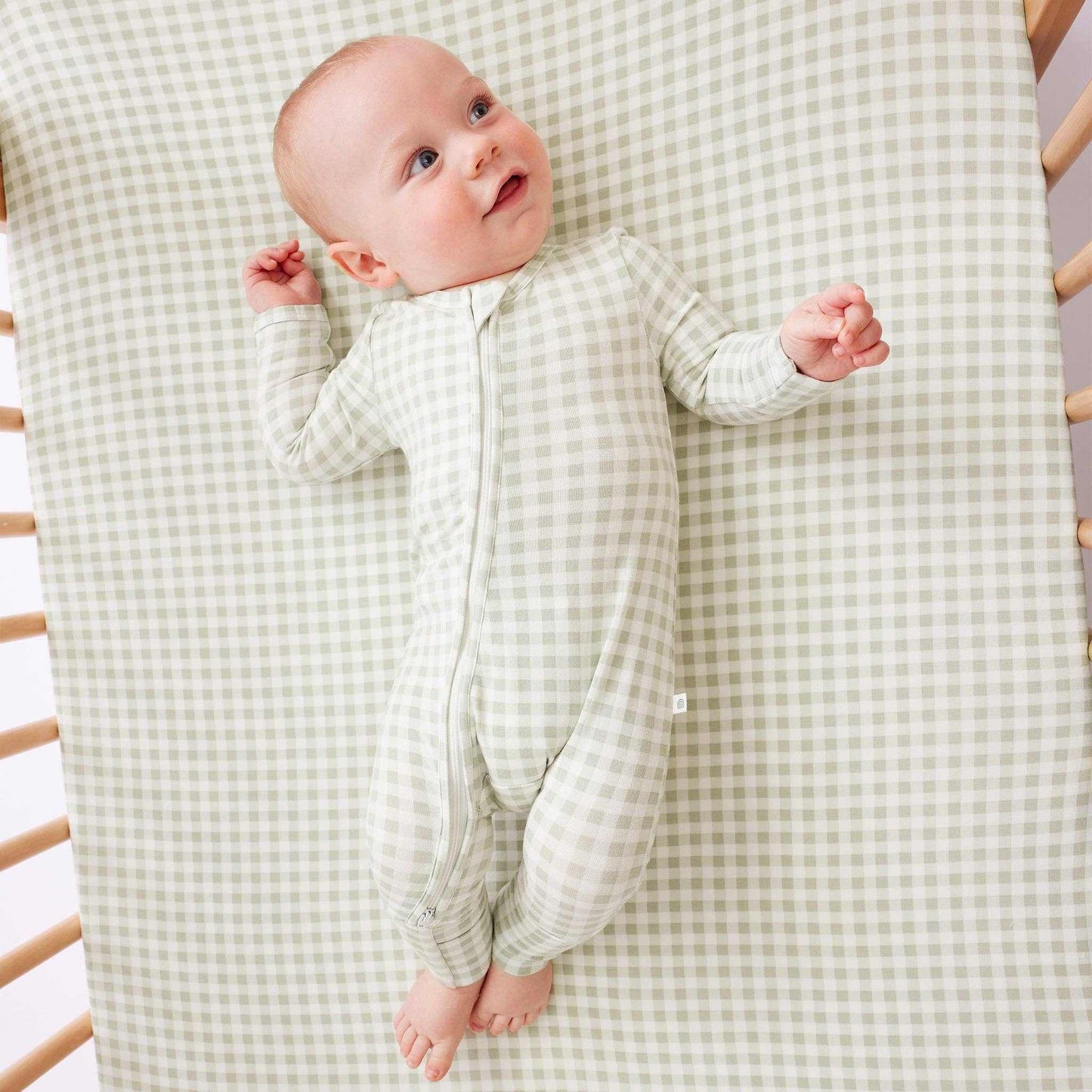 Baby wearing Kynd Onesie sage gingham soft sustainable fabric with two-way zip and fold-over cuffs