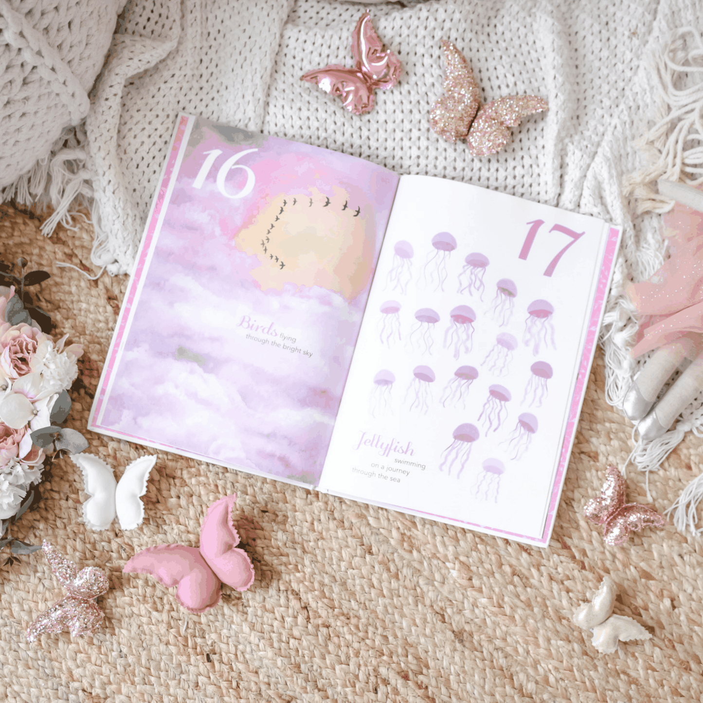 Open pages of The Enchanting 123 children's book featuring illustrated counting of birds and jellyfish with pink and purple tones surrounded by decorative butterflies