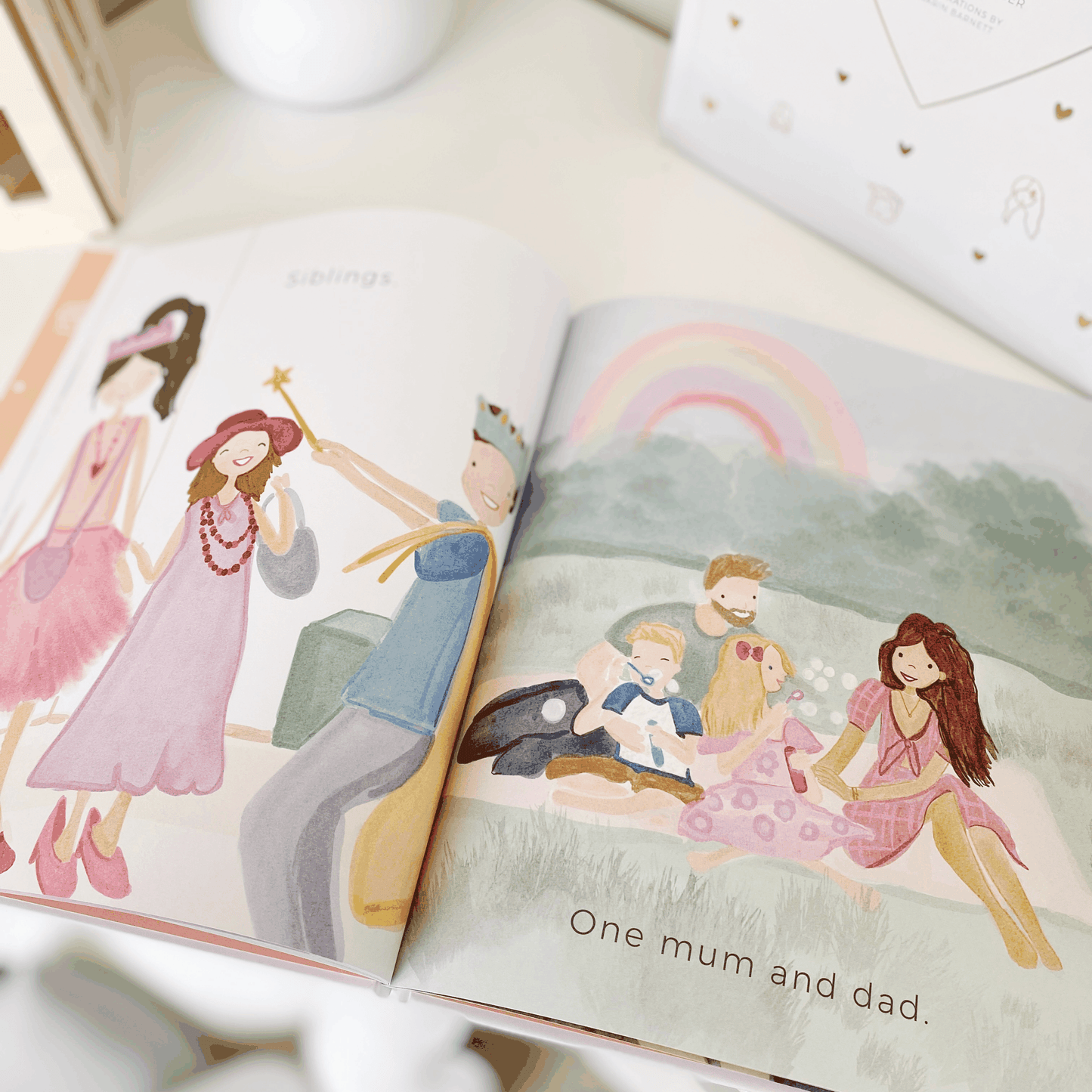 Open pages of My Family - Illustrated Children's Book showing diverse family illustrations with gold foil and matt white cover detail.