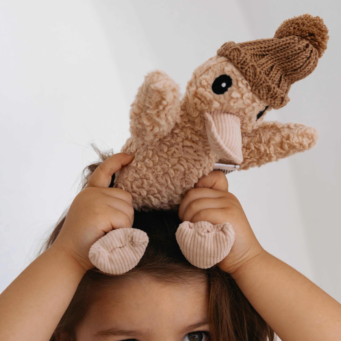 Poppy the Duck plush toy with knitted hat held by child