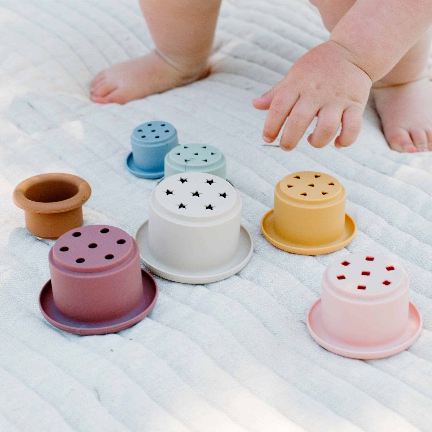 Kynd Silicone Stacking Cups in pastel colors with star, heart, and geometric shape cutouts for baby play and stacking fun.