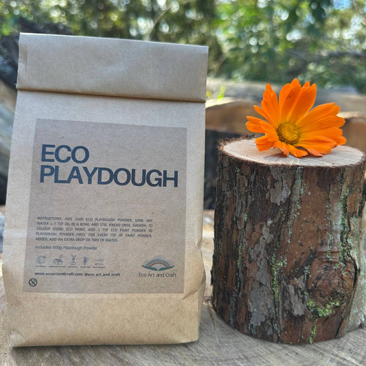 Bag of Eco Playdough with an orange flower on a wooden stump outdoors