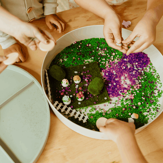 Children playing with Sensory Kits Fairy Garden featuring faux grass, fairy figurines, sequins, and petals in a tray