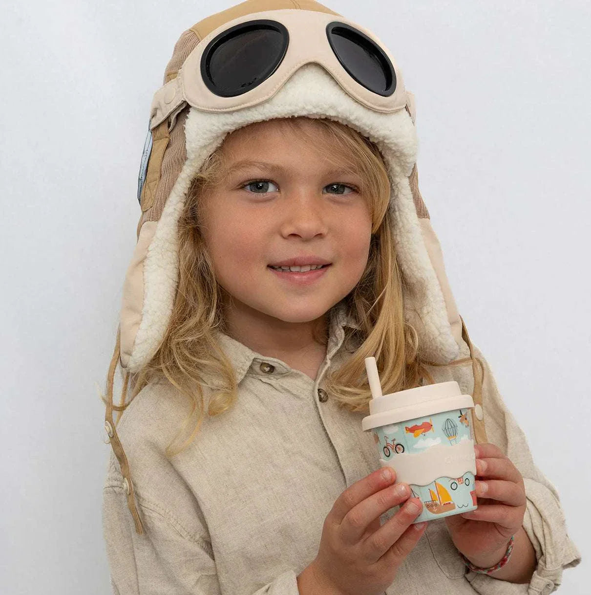 Child holding eco-friendly Vehicles Babychino Cup with silicone lid and colorful vehicle illustrations