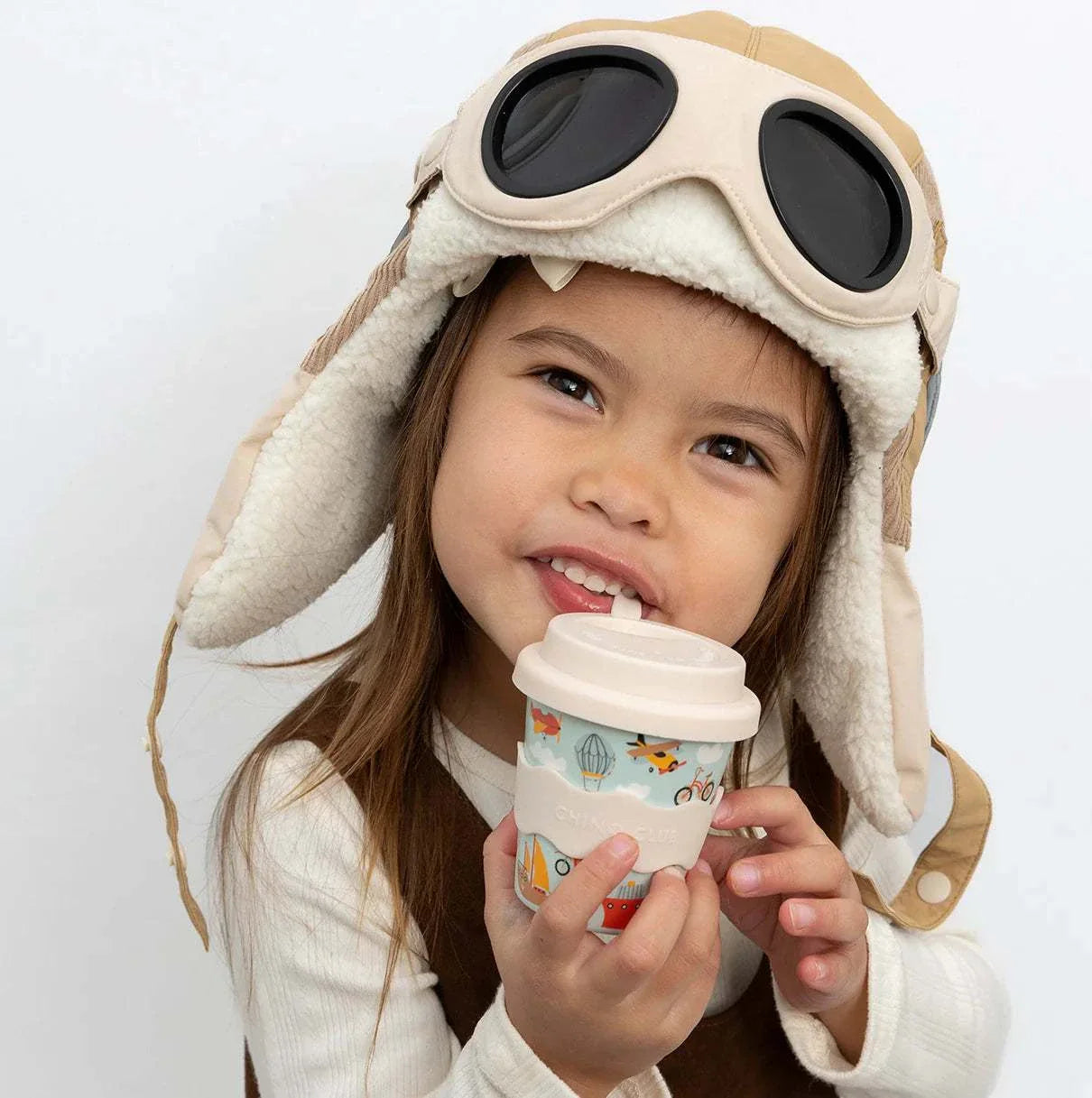 Child holding eco-friendly Vehicles Babychino Cup with silicone lid and colorful vehicle illustrations